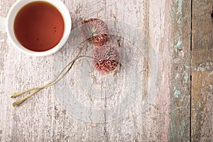 Cup of hot tea and two dried flowers on a background of peeling paint with room for text