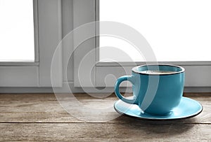 Cup of hot winter drink on wooden sill near window, space for text.