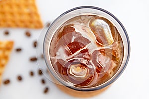 A cup of Iced Americano Coffee with ice cubes placed on a marble table in a coffee shop. Top view of a glass of coffee