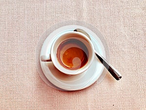 Cup of Italian espresso coffee on a powder pink tablecloth