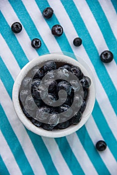 A Cup Of Juicy Blueberries At A Bright Blue Stripy Background