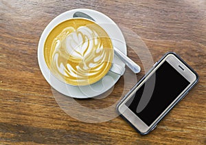 Cup of Latte art coffee with smart phone