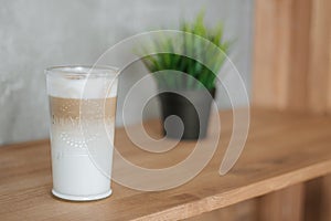 Cup of latte on the bar, Cup of coffee on the wooden bar with green grass in a vase, Latte