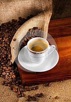 Cup of latte coffee and coffee beans on old wooden background