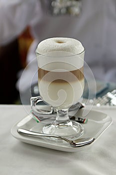 A cup of latte macchiato on the table with white tablecloth