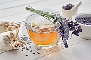 Cup of lavender tea and lavender flowers. Mortars of dry lavender and sachets on background. Alternative medicine photo