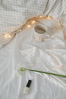 Cup of lemon tea, daffodil flower and accessorries on bed. Breakfast in bed. Morning. Spring.