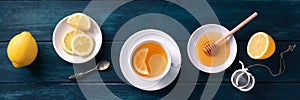 A cup of lemon tea and honey panorama on a dark rustic wooden background