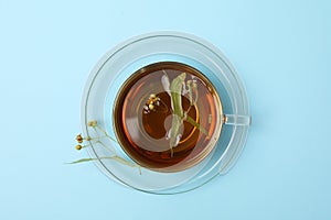 Cup linden tea on blue background, top view