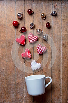 Cup on lying on side with Christmas baubles and heart shapes