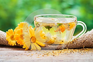 Cup of marigold tea and calendula flowers outdoors