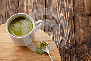 Cup of Matcha tea on a round wooden tray