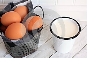 Cup of milk and brown Eggs in metal bucket