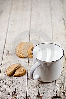 Cup of milk and some fresh baked oat cookies on rustic wooden table background