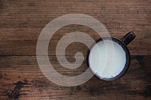 Cup of milk on wooden background. Brown ceramic mug with fresh milk on wood table. View from above.