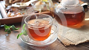 Cup of mint herbal tea with small bowl with honey on the tray.