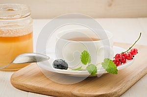 Cup of with mint tea and berries and jar of honey on a wooden tray/Cup of with mint tea and berries and jar of honey on a wooden