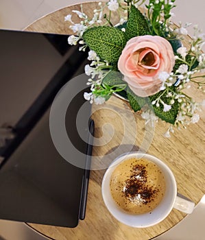 A cup of moccacino coffee, flowers and a tablet photo
