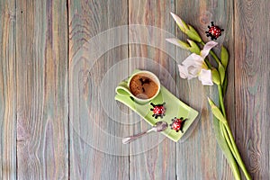 A cup with morning coffee, candies and a bouquet of white irises