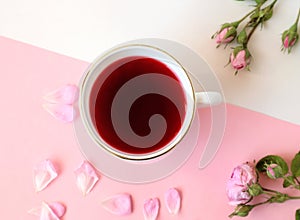 A Cup of morning tea with branches and rose petals on a pastel background, top view, close-up, place for the inscription