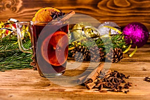 Cup of mulled wine with cinnamon, christmas decorations and fir tree branches on wooden table