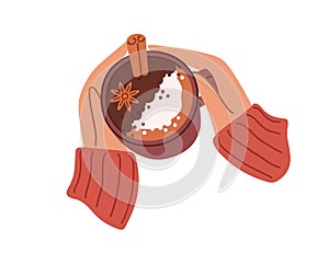 Cup of mulled wine with winter spices in hands in warm sweater. Mug of gluhwein, hot spicy Christmas drink with cinnamon photo