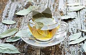 Cup of natural bay leaf herbal tea on wooden table