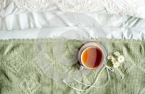 cup of natural herbal tea from mint and lemon balm in bed,morning close up. Cozy atmosphere.Openwork lace,cotton white blanket,