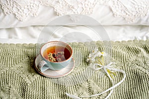 cup of natural herbal tea from mint and lemon balm in bed,morning close up. Cozy atmosphere.Openwork lace,cotton white blanket,
