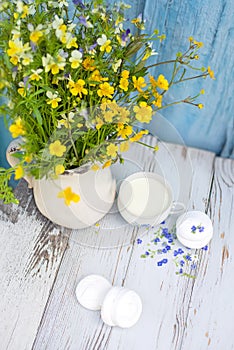 cup with natural homemade milk and sweet marshmallows on a wooden background. A bouquet of wildflowers and summer mood,