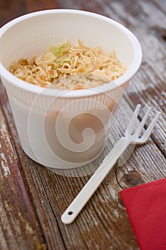 Cup-a-noodles pasta ramen in plastic cup on wood table