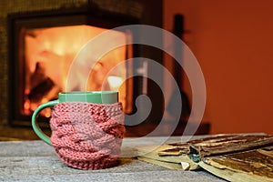 Cup, old book on vintage wood near fireplace