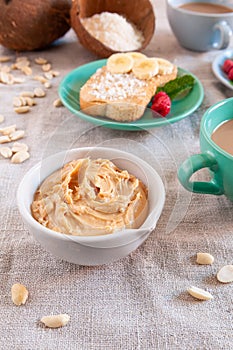 Cup with peanut butter and coke flakes. In the background there is a sandwich and cups of drinks. Close-up