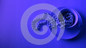 Cup of pearl necklace below neon light. With copy space to insert text. Wide screen, flat lay view.