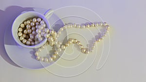 Cup of pearl necklace on a white background. With copy space to insert text. Wide screen, flat lay view.