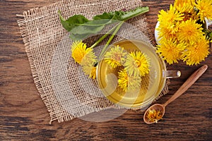 Cup ph healthy dandelion tea on vintage wooden background. Fresh herbs.