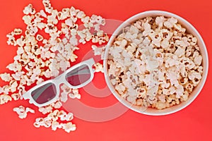 Cup with popcorn and 3d glasses on a red background, top view. Cinema Concept. Flat lay