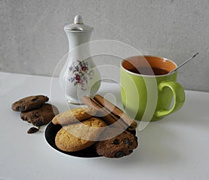 Cup and pot of coffee and coffee beans, cookies with cinnamon, chocolate candy, isolated on white.