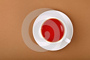 Cup of red black tea on white saucer