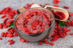 Cup with red goji berry on gray stone background. Selective focus, above view