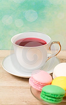 Cup of red tea and colored cakes