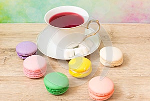 Cup of red tea and colored cakes