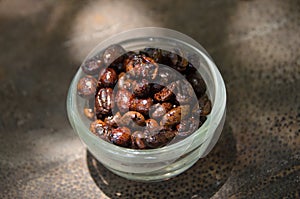 A cup of Roasted coffee beans on oldwood table