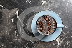 Cup with roasted coffee beans and space for text on grey background