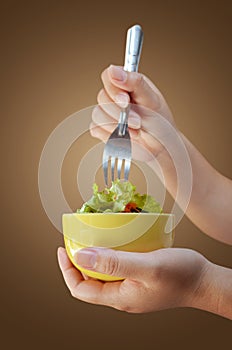 Cup of salad in the hand and fork