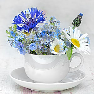 Cup and saucer with bunch of wild flowers