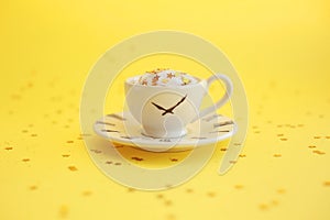 A cup and a saucer with clockface icon, on yellow background with glitter