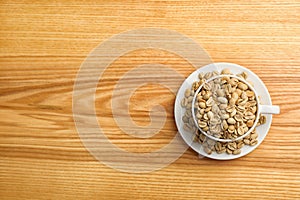 Cup and saucer with green coffee beans on wooden background, top view