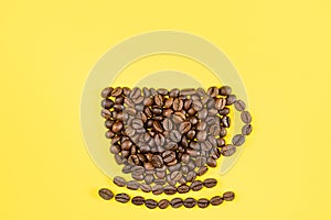 A cup and saucer is lined with coffee beans on a yellow background.