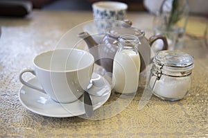 Cup and saucer with a teapot, milk and sugar